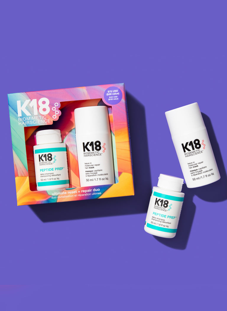 a-product-image-featuring-a-colorful-packaging-box-with-k18-branding-alongside-two-bottles-of-molecular-repair-mask-and-the-detox-shampoo-placed-outside-the-box-on-a-purple-background